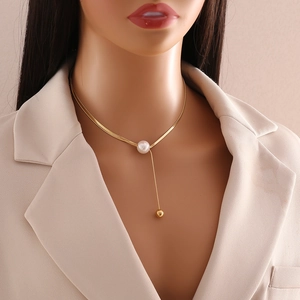 Detail of gold snake chain necklace featuring a white pearl and elegant fringe drop charm