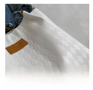Macro shot of white quilted faux leather texture with brown fashion bags brand label