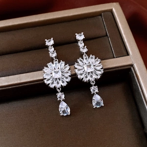 Macro view of silver flower earrings with clear cubic zirconia and teardrop pendants