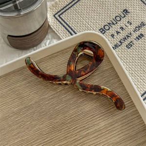 Close-up of tortoise shell pattern claw clip on wooden tray with a lifestyle aesthetic