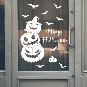 Close-up of Halloween window stickers featuring stacked pumpkins and bats on a glass door