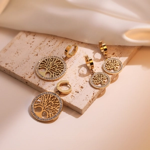 Golden Tree of Life jewelry set with earrings and necklace pendant on stone background