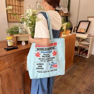 Detail of light blue canvas tote bag with vintage print worn on the shoulder