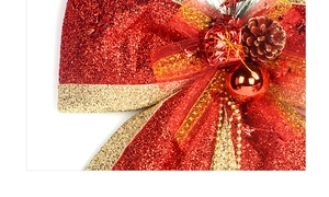 Detail of red and gold Christmas bow with pine cones, gift boxes and glittery finish
