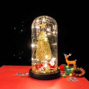 Detail of a Christmas glass dome with golden tree, Santa Claus, and warm LED fairy lights