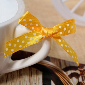 Close-up of yellow satin polka dot bow tied on a white ceramic mug handle