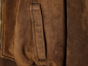 Vue détaillée du tissu en suédine marron de la veste avec fermeture éclair latérale