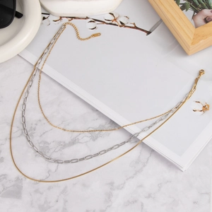 Elegant multi-layer necklace in 18K gold and silver steel on marble surface