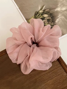 Detail of pink organza oversized scrunchie with soft mesh pleats on wooden tray