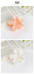 Detailed view of frangipani flower hair claws in peach pink and cream white colors