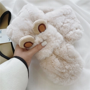 Close-up of fluffy cream plush scarf with cute cartoon bear ear details and soft texture