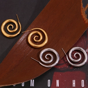 Detail of 18K gold and silver plated spiral swirl earrings on vintage wood and magazine props