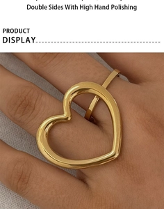 Detailed view of polished gold stainless steel hollow heart ring worn on a finger