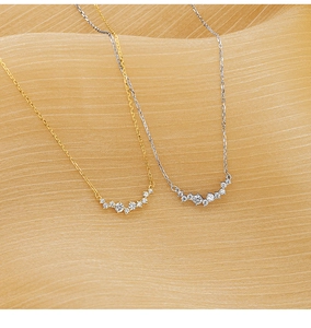 Close-up of gold and silver plated S925 necklaces with zircon on gold silk fabric