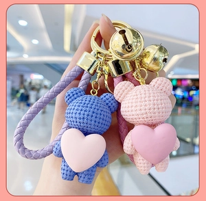 Close-up of pink and blue woven texture bear keychains with golden bells and straps