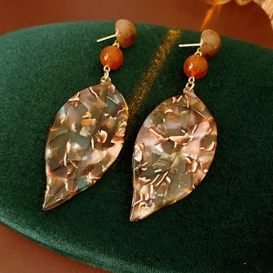Detail of tortoise shell acetate leaf earrings on green velvet display stand