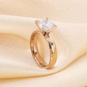 Close-up of rose gold four-prong ring with a large round cubic zirconia on silk