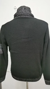 Dettaglio del maglione in maglia nera con particolari screziati grigi su collo e polsini