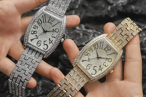 Close-up of gold and silver tonneau quartz watches with full crystal pavé dial and strap