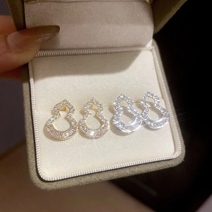 Macro detail of gold and silver hollow gourd stud earrings set with sparkling zircons