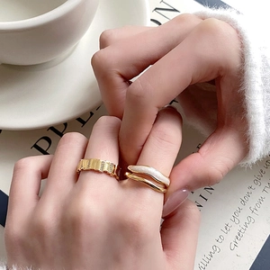 Luxe gold textured band and double-layered wave ring shown in a stylish lifestyle setting