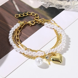 Detail view of multi-layer baroque pearl bracelet with gold heart and key charms