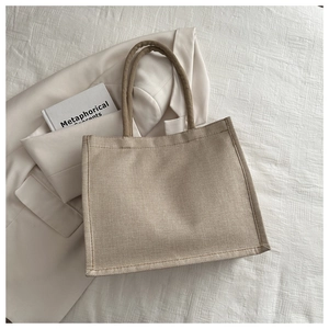 Detailed top view of natural jute tote bag with thick rope handles on a white bedding