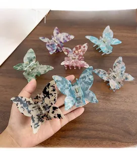 Detail view of seven colorful butterfly hair claws with iridescent marble texture on wood