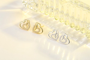 Detail of interlocking heart stud earrings with cubic zirconia inlay in gold and silver