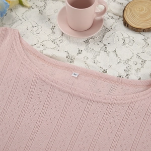 Close-up of pink pointelle knit fabric showing breathable texture and round neckline details