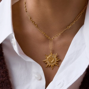 Macro detail of sun and moon pendant necklace with crystal inlay on a gold chain