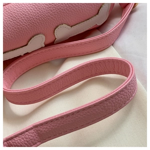 Detail of pink lychee grain leather shoulder strap with white edging and precise stitching