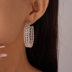 Detailed close-up of silver-tone C-shape hoop earrings with a woven metal texture on a model
