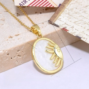 Detail of gold oval pendant with faux shell inlay and sun relief design on beige stone