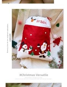 Détail du sac cadeau de Noël rouge et blanc avec cordon, motifs Père Noël et bonhomme de neige