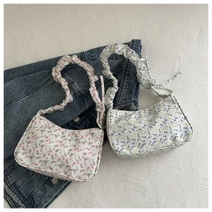 Detailed view of floral shoulder bags in pink and purple with pleated handle straps
