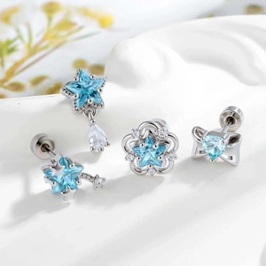 Silver star and heart cartilage earrings set with blue zircon stones on white display