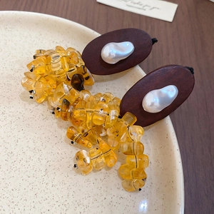 Detailed shot of wooden oval earrings with amber resin beads and baroque pearls on ceramic