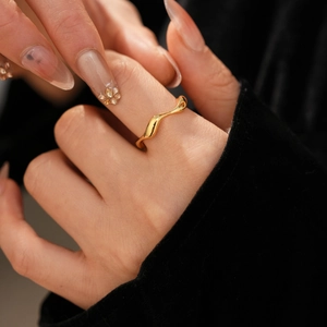 Detail of 18k gold plated wave ring with irregular liquid metal texture on finger