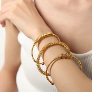 Détails de trois bracelets en acier doré avec texture ressort et design géométrique chic