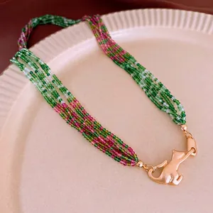 Multilayer green and pink beaded necklace with a golden cat clasp on a display tray