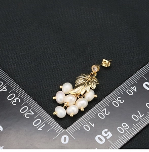 Detailed view of pearl drop earrings in 18k gold plating with a metric size ruler