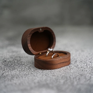 Close-up of dual-slot walnut wood ring box with velvet lining and silver couple rings