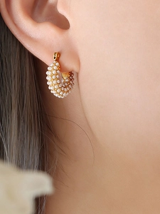 Close-up of gold hoop earrings with pavé set pearls on a female model side profile