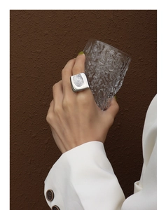 Detailansicht eines silbernen quadratischen Rings mit Fingerabdruck-Struktur am Finger