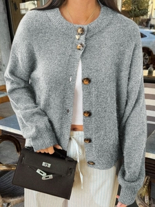 Détail d'un cardigan gris en maille avec des boutons marrons et un col rond classique