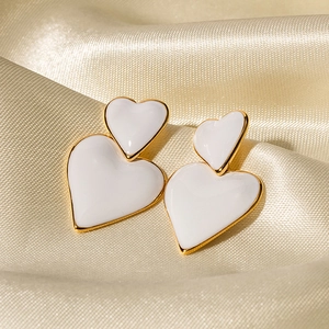 Dettaglio di orecchini a doppio cuore placcati in oro 18k con smalto bianco su seta