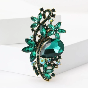 Macro view of vintage gold alloy brooch featuring teardrop and marquise green crystals