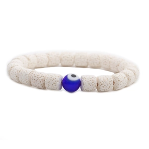 Nahaufnahme weißer Lava-Steinperlen und dunkelblauer Evil-Eye-Anhänger auf Perlenarmband