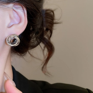 Détail de boucles d'oreilles rondes évidées en argent portées par un mannequin de profil